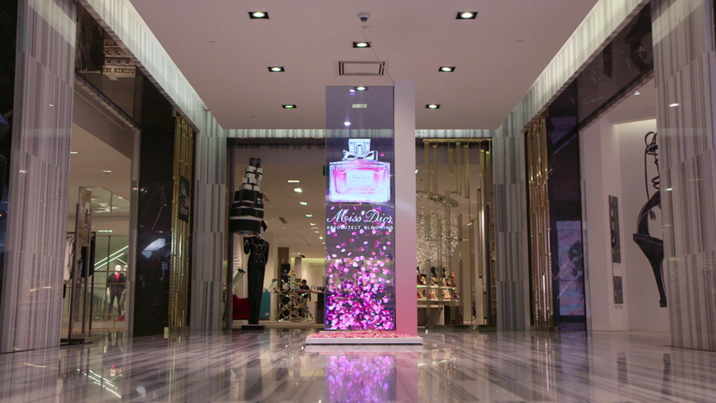 Tall digital fragrance display column within a luxury retail environment