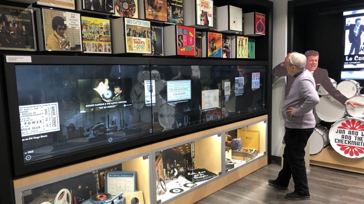 Museum visitor exploring a wide interactive display integrated with a music collection