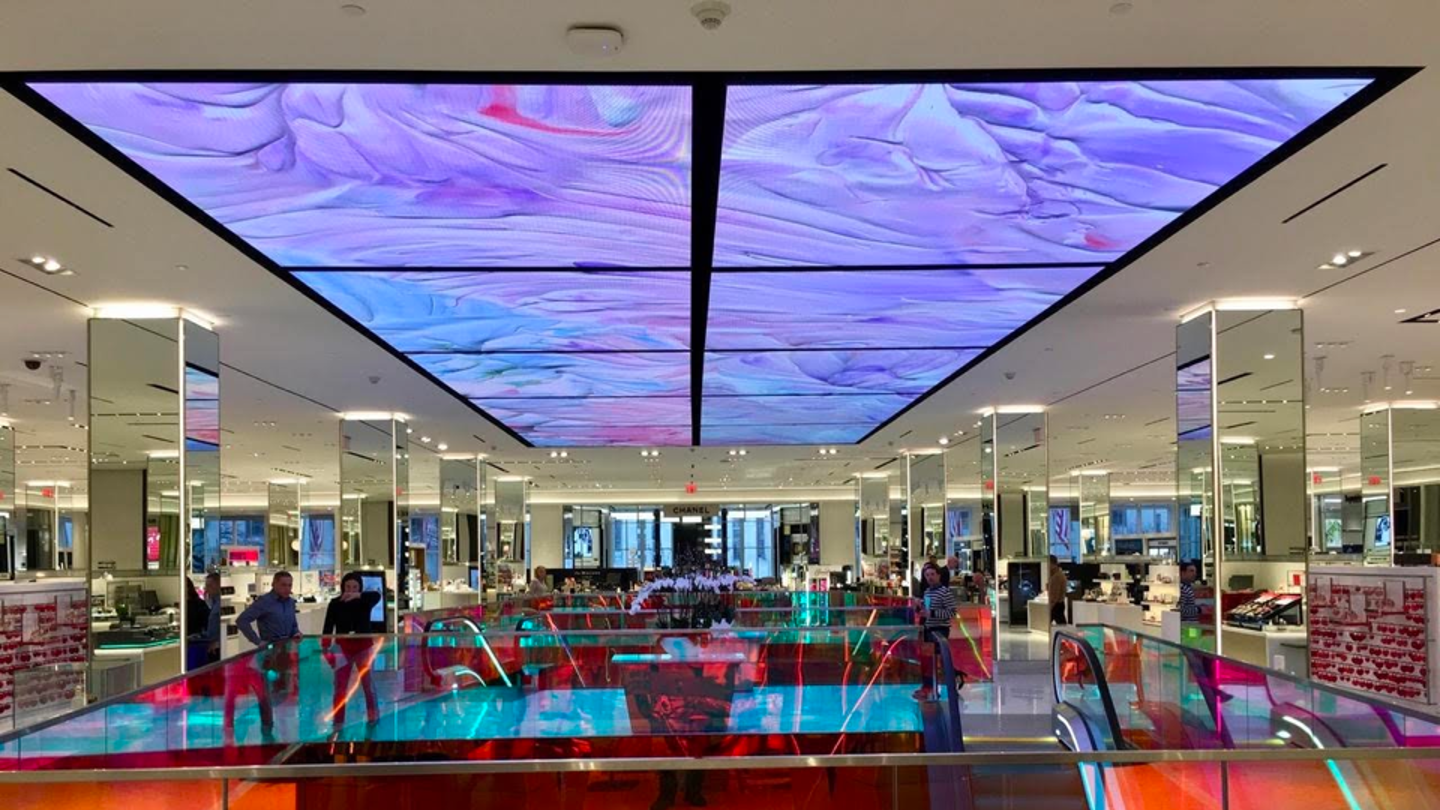 Large-format digital ceiling above a mirrored beauty retail floor